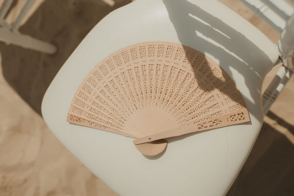 Fächer als Gastgeschenk auf einem Stuhl bei einer Strandhochzeit