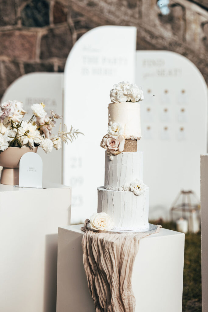 Hochzeitstorte auf weißen Podesten beim Styled Shoot im Schloss Kittendorf